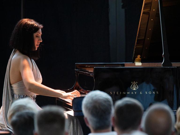 Alexandra Dariescu sitzt an einem großen Flügel und spielt. Sie trägt ein silbernes Kleid. Das Publikum hört aufmerksam zu. Das Konzert fand im Rahmen des Klavier-Festival Ruhr statt.
