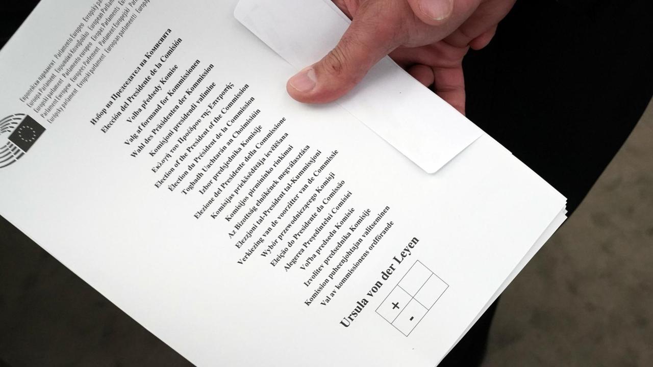 Ein Mann hält vor der Wahl einen Stimmzettel im Plenarsaal.
