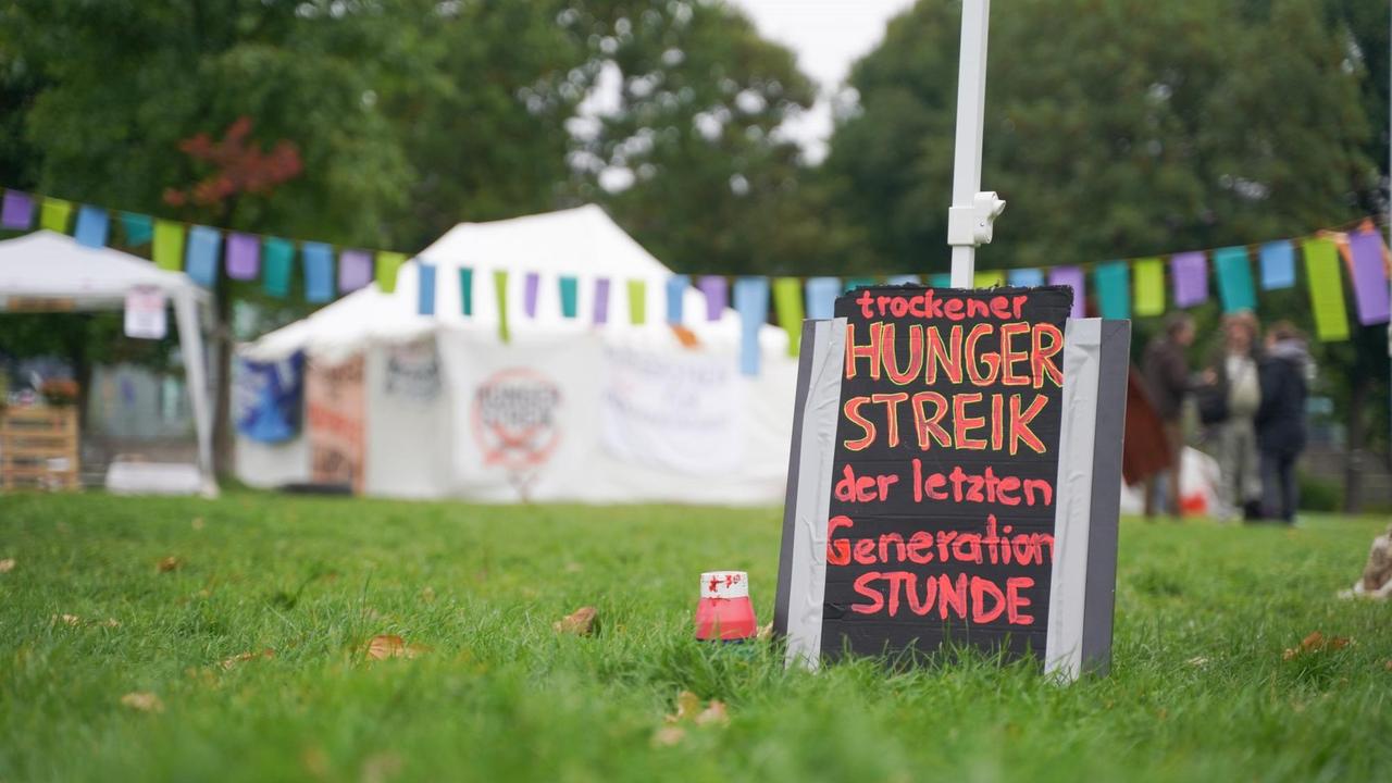 Ein Schild mit der Aufschrift "trockener Hungerstreik der letzten Generation Stunde" steht im Spreebogenpark und soll darüber informieren, dass die verbliebenen Streikenden auch aufgehört haben zu trinken.