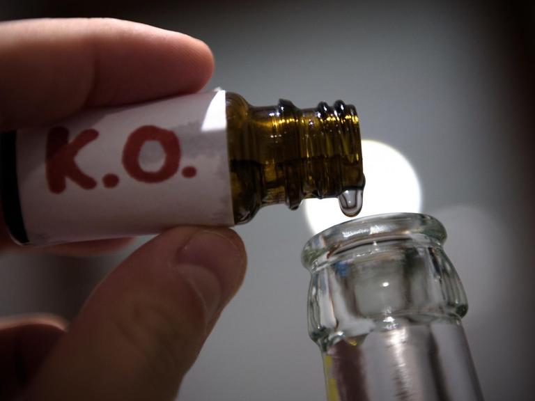In einer gestellten Szene werden "K.O.- Tropfen" in eine Bierflasche gefüllt