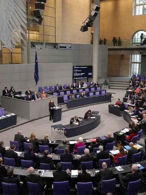 Der Blick auf das gut besetzte Plenum des Bundestages, am Rednerpult Kanzlerin Angela Merkel.