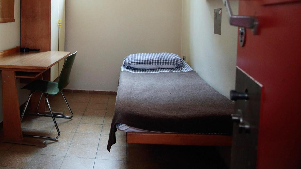 Eine Gefängniszelle in Deutschland: mit Bett, Tisch, Stuhl, Schrank und Waschbecken.
