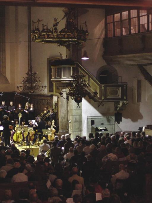 Blick in einen Kirchenraum, in dessen Altarbereich ein Orchester mit historischen Instrumenten spielt.