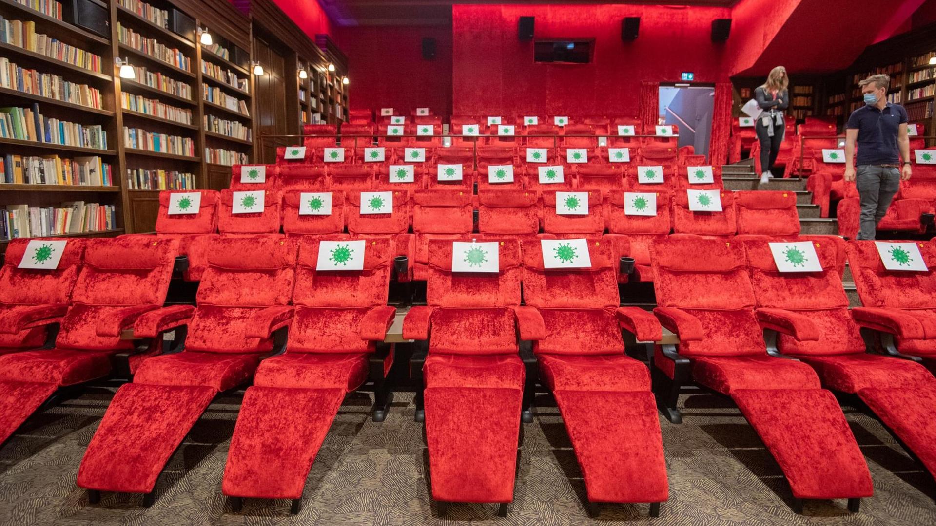 Einzelne Sitzplätze in einem Kinosaal sind mit Zetteln mit aufgedrucktem angedeuteten Virus-Symbol abgesperrt, damit Kino-Besucher einen Abstand von 1,5 Meter zueinander einhalten können.
