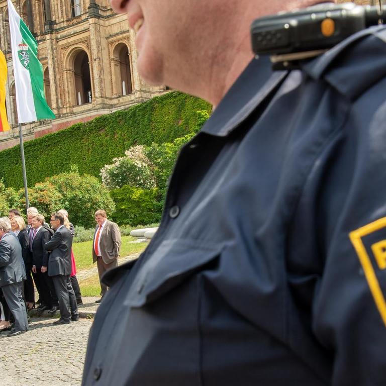15.05.2018, Bayern, München. Mitglieder der SPD-Landtagsfraktion nehmen vor Beginn der Plenarsitzung im Landtag an einer Plakat-Aktion gegen das Polizeiaufgabengesetz (PAG) teil und werden von einem Polizisten in Uniform beobachtet. Das PAG soll am späten Abend im bayerischen Landtag verabschiedet werden. Foto: Peter Kneffel/dpa | Verwendung weltweit