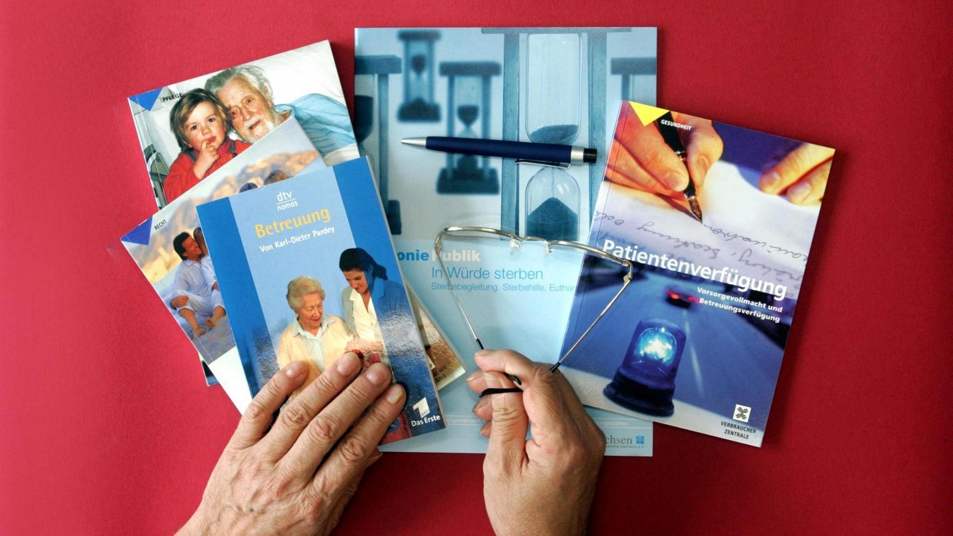 Bücher, Broschüren und Nachschlagewerke, die sich mit Patientenverfügungen sowie der Pflege und Sterbehilfe befassen, liegen auf einem roten Tisch.