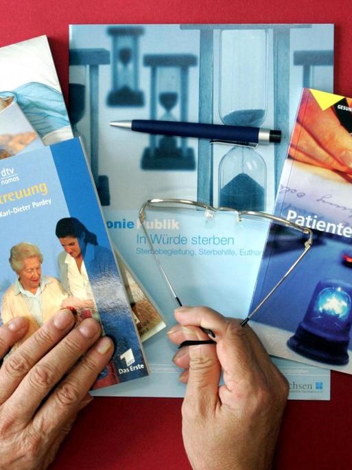 Bücher, Broschüren und Nachschlagewerke, die sich mit Patientenverfügungen sowie der Pflege und Sterbehilfe befassen, liegen auf einem roten Tisch.