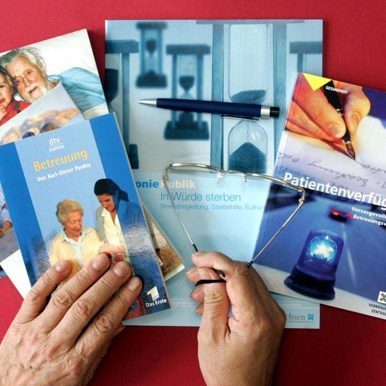 Bücher, Broschüren und Nachschlagewerke, die sich mit Patientenverfügungen sowie der Pflege und Sterbehilfe befassen, liegen auf einem roten Tisch. 