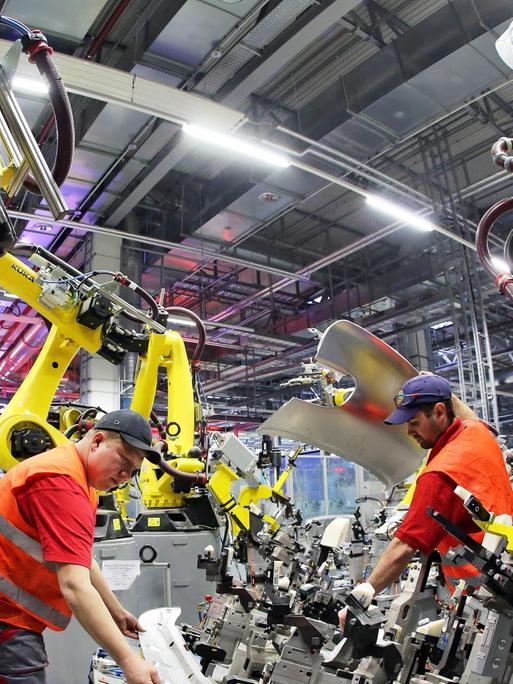 Mechatroniker installieren einen Roboter in der Karosseriefertigung des Sportwagenbauers Porsche.
