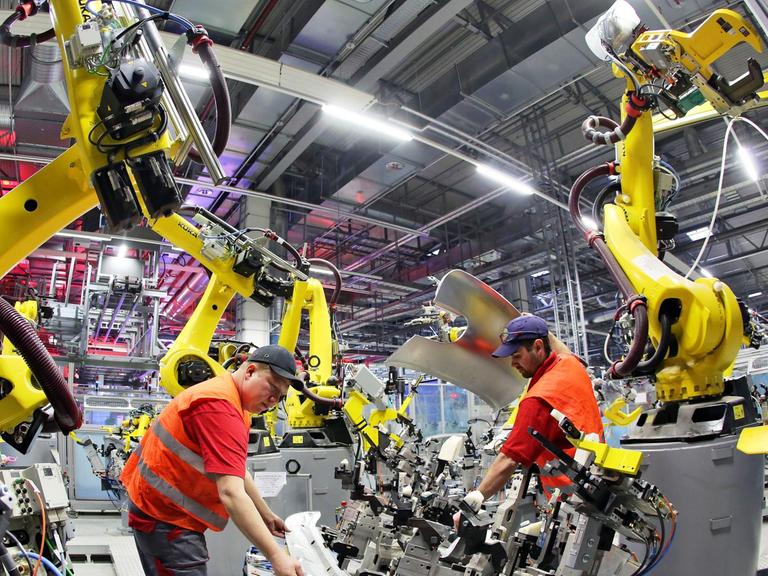 Mechatroniker installieren einen Roboter in der Karosseriefertigung des Sportwagenbauers Porsche.