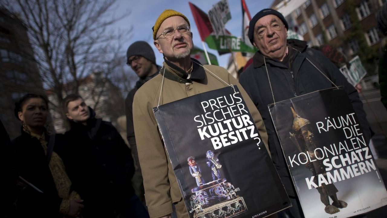 Demonstranten auf dem Gedenkmarsch "Kolonialgeschichte Deutschlands" mit Schildern um den Hals.