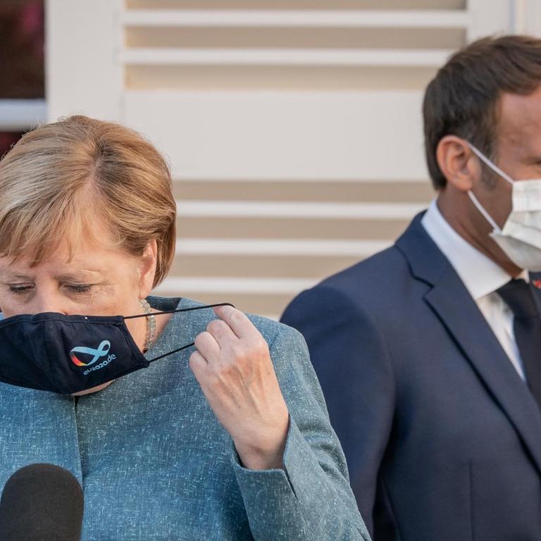 Emmanuel Macron, Präsident von Frankreich, kommt hinter Bundeskanzlerin Angela Merkel (CDU), zur Pressekonferenz in der Sommerresidenz des Staatschefs, dem Fort de Bregancon. Die frühere Festung liegt auf einem Felsen an der Mittelmeerküste in der Nähe von Toulon.