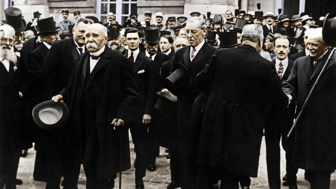 Georges Clemenceau und Woodrow Wilson verlassen mit anderen Männern das Schloß von Versailles nach der Vertragsunterzeichnung.