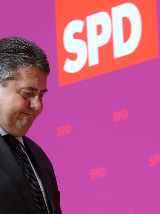 SPD-Vorsitzender Sigmar Gabriel geht vor einer purpurfarbenen Wand mit rotem SPD-Logo entlang