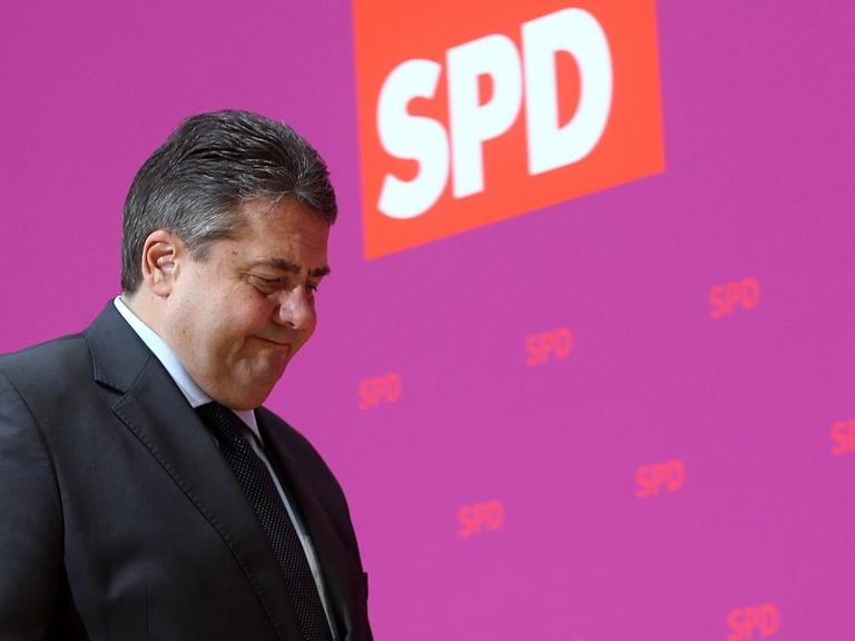 SPD-Vorsitzender Sigmar Gabriel geht vor einer purpurfarbenen Wand mit rotem SPD-Logo entlang