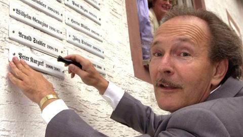 Der Stadtschreiber des Frankfurter Stadtteils Bergen-Enkheim, Peter Kurzeck, befestigt am 1.9.2000 ein Metallschild mit seinem Namen an der Fassade des Stadtschreiberhauses