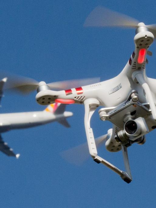 Das Foto zeigt eine private Drohne, dahinter in weiter Entfernung ein Flugzeug im Anflug auf den Flughafen Düsseldorf.