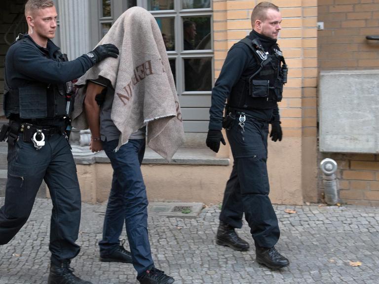 Polizisten in Berlin führen einen verdächtigen Mann nach einer Razzia gegen Mitglieder arabischer Großfamilien ab.
