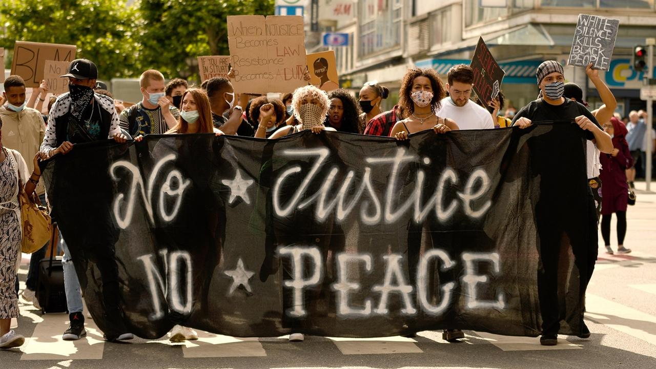 "Black Lives Matter"-Demonstranten laufen hinter einem Plakat mit der Aufschrift "No Justice, No Peace".