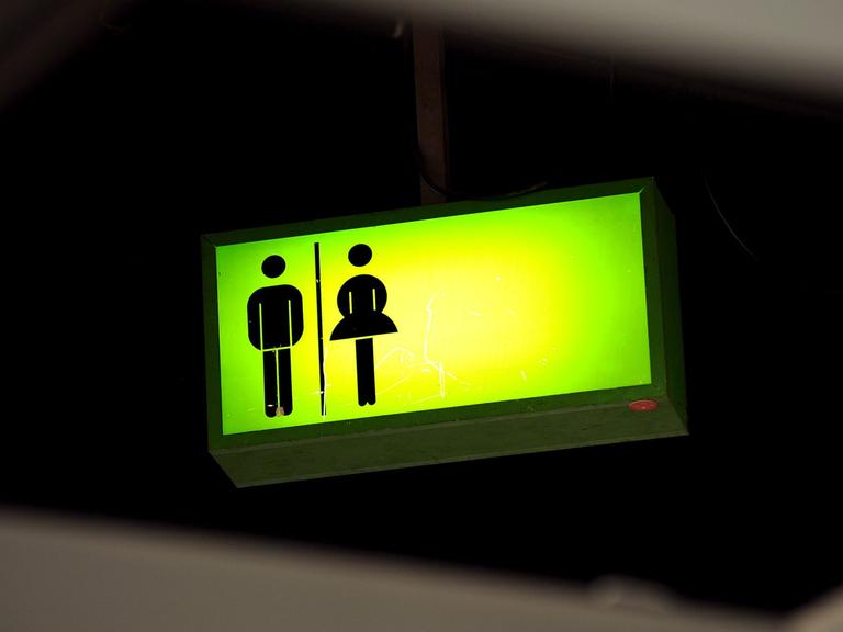Ein grün leuchtendes Toiletten-Hinweisschild hängt auf dem Messegelände in Frankfurt am Main unter der Decke