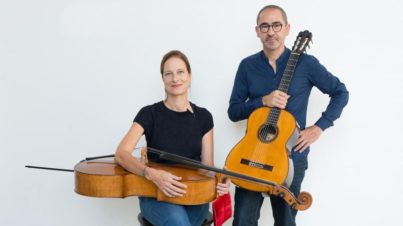 Anja Lechner hat ihr Cello sitzend quer auf dem Schoß liegen, neben ihr steht Pablo Márquez mit seiner Gitarre in der Hand.