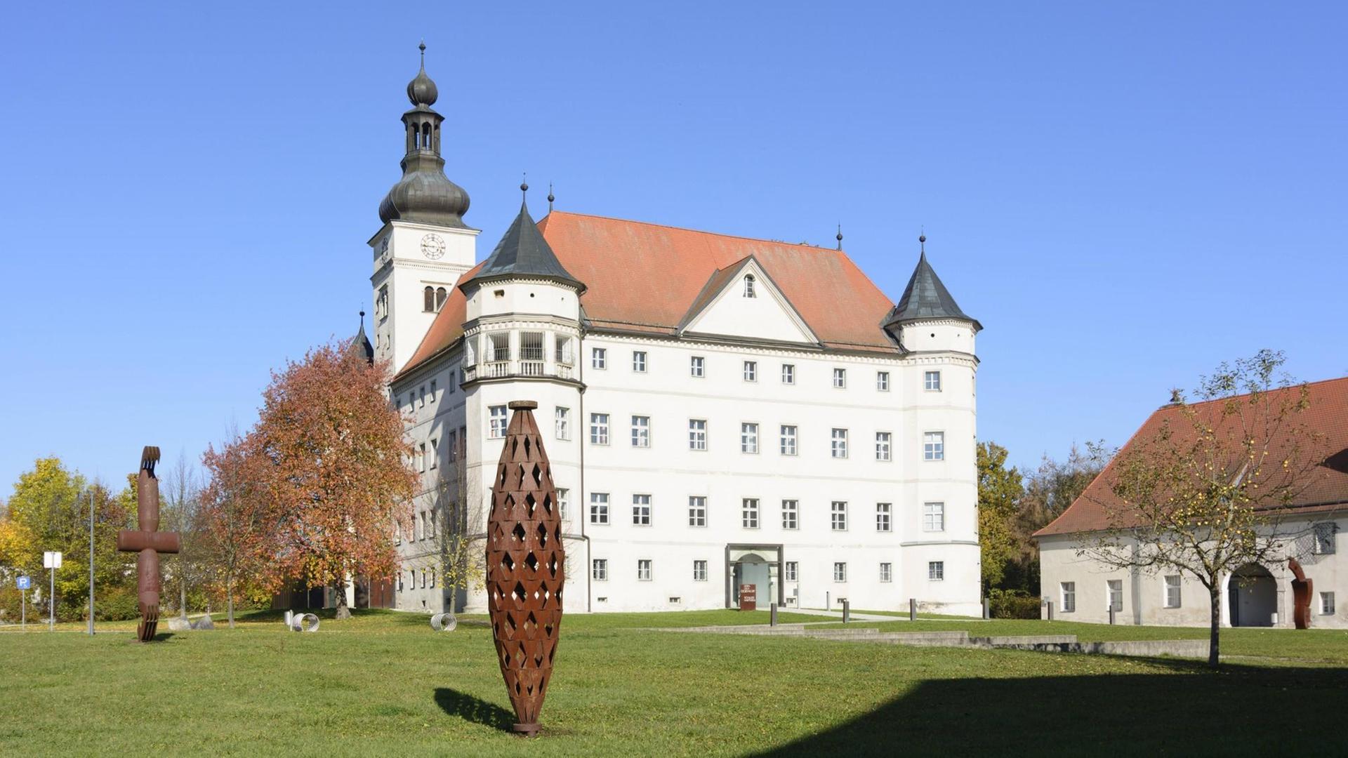 Blick auf das Schloss Hartheim umgeben von abstrakten Skulpturen aus Metall