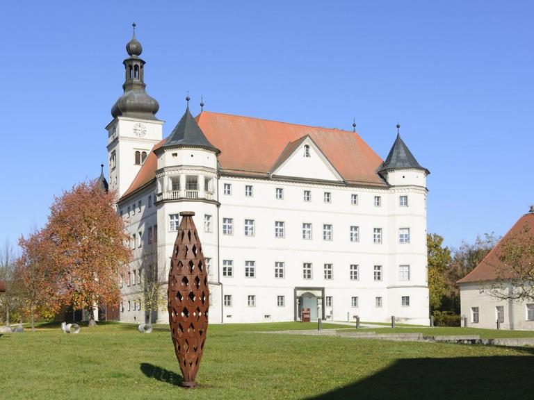 Blick auf das Schloss Hartheim umgeben von abstrakten Skulpturen aus Metall