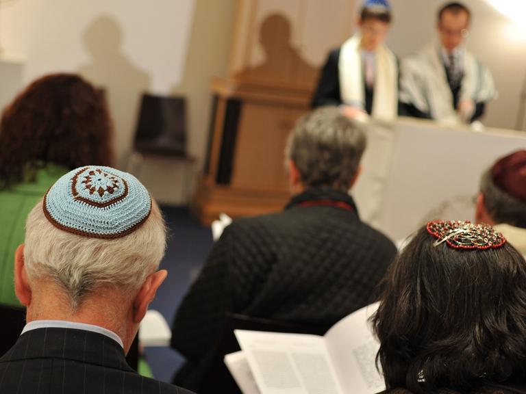 Bar-Mitzwa-Gottesdienst in der liberalen jüdischen Gemeinde Beth Shalom in München. Zu sehen sind Gemeindemitglieder mit Kippa, weiter hinten der Rabbiner mit einem Jungen, der auf die Bar Mitzwa vorbereitet wird.