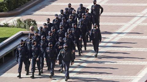 Polizeikräfte marschieren in Reih und Glied.