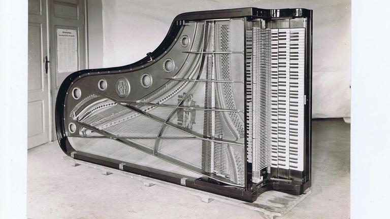Blick in einen hochkant gestellten Flügel mit erweiterter Tastatur.