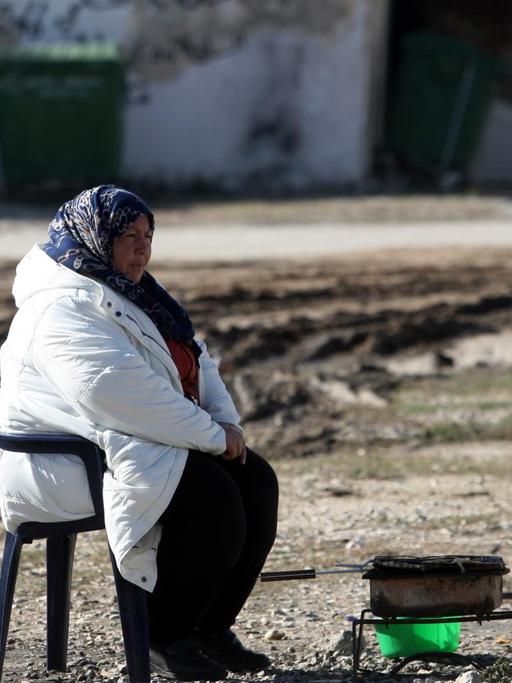 Eine Frau sitzt an einem Camping-Kocher in einem Flüchtlingslager in Thessaloniki, Griechenland.