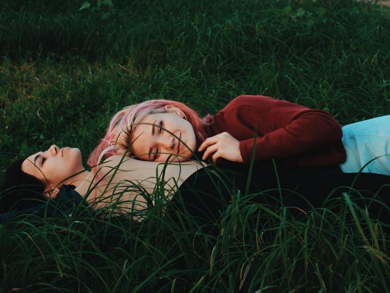 Zwei Frauen liegen aneinander geschmiegt im Gras
