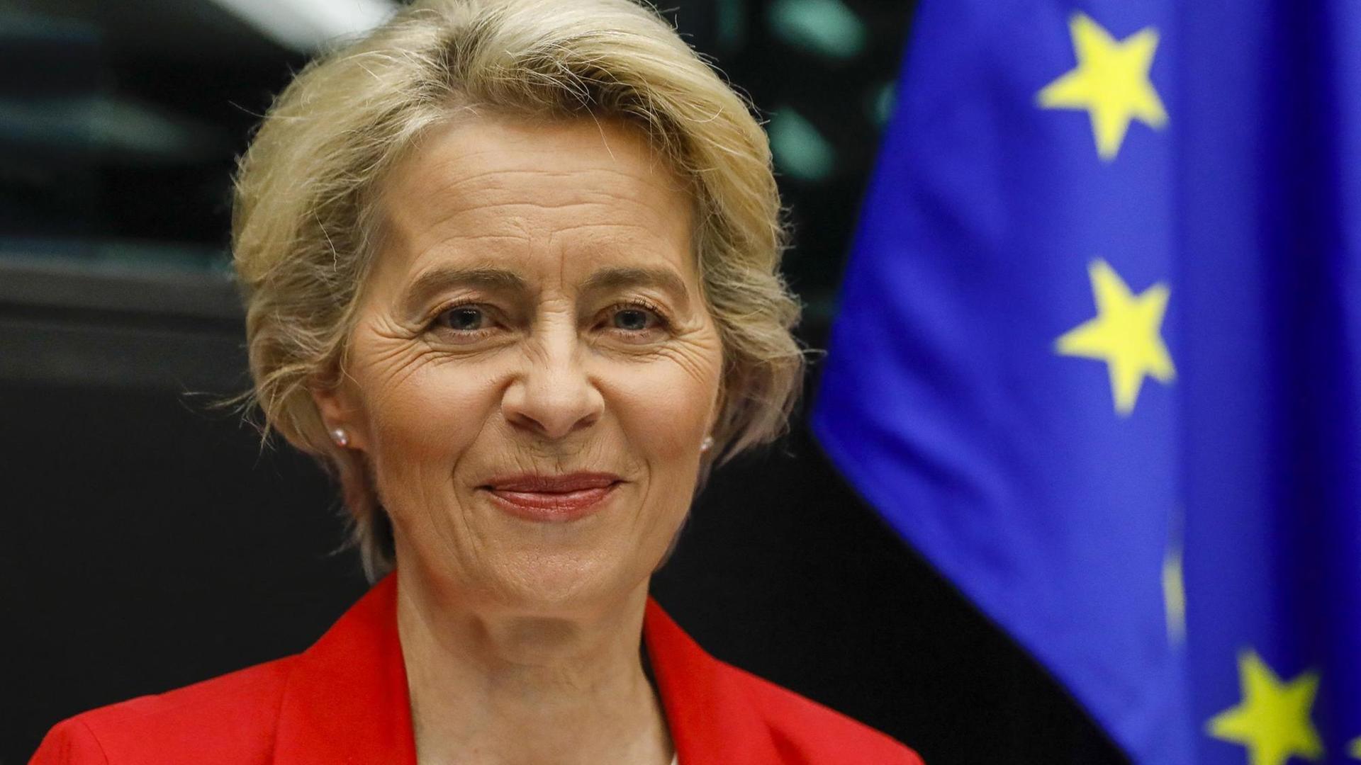 Porträtbild von EU-Kommissionspräsidentin Ursula von der Leyen neben einer EU-Flagge