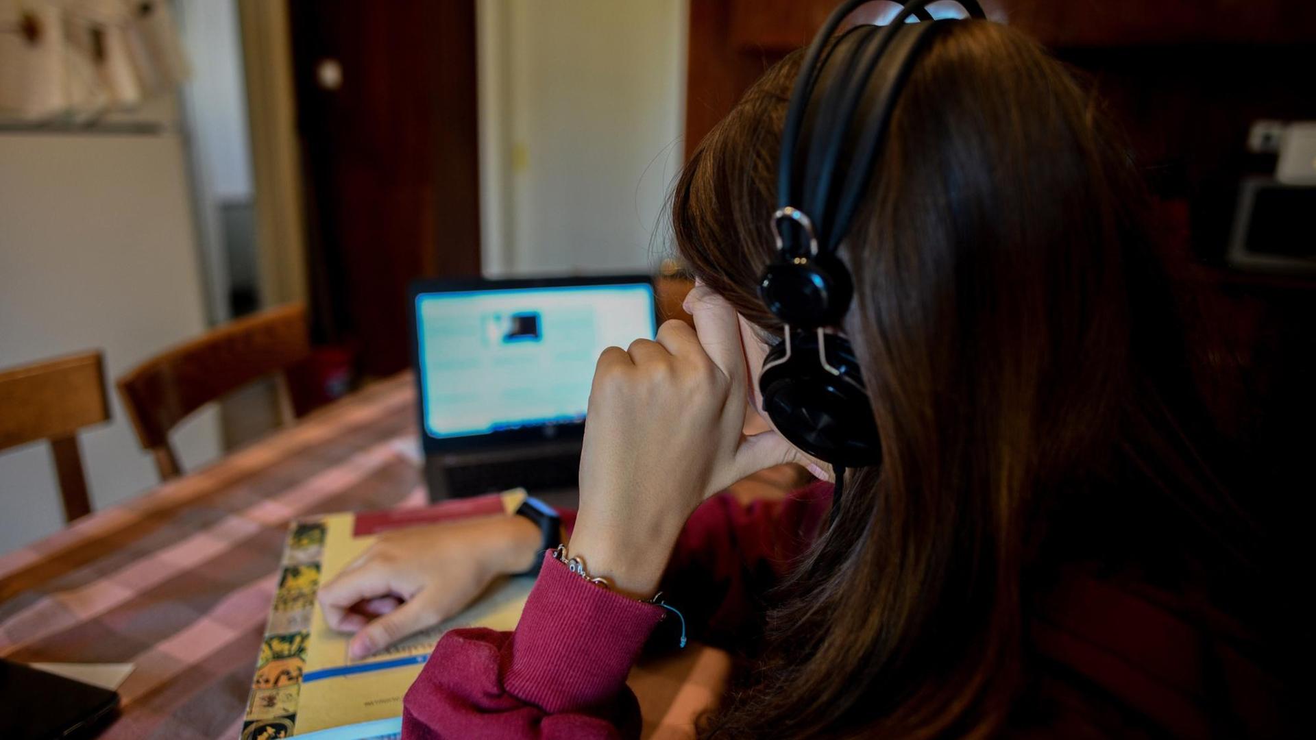 Das Bild zeigt eine Schülerin beim Online-Unterricht vor einem Laptop am Küchentisch.