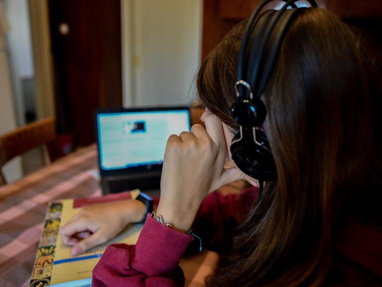 Das Bild zeigt eine Schülerin beim Online-Unterricht vor einem Laptop am Küchentisch.