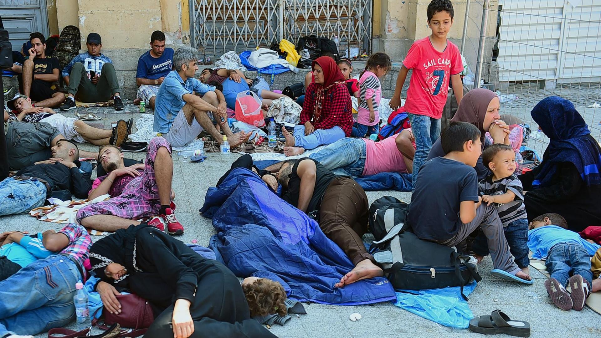 Erschöpfte Flüchtlinge sitzen und liegen vor dem Ostbahnhof in Budapest.