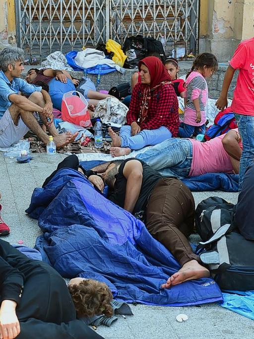 Erschöpfte Flüchtlinge sitzen und liegen vor dem Ostbahnhof in Budapest.