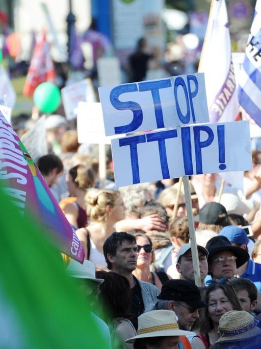 Demonstranten tragen am 04.06.2015 in München (Bayern) bei einer Demonstration gegen den G7-Gipfel am Odeonsplatz Plakate und Fahnen, wobei auf einem Plakat "Stop TTIP!" zu lesen ist.