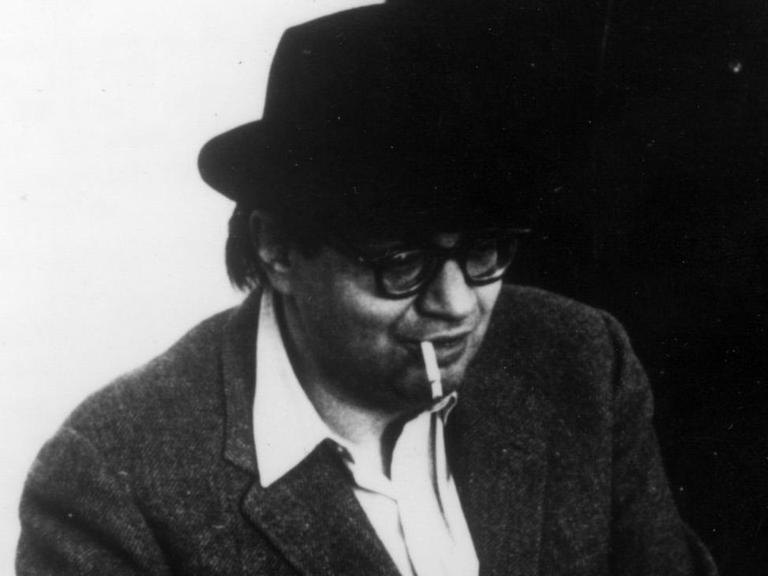 Der Komponist sitzt mit seinem für ihn typischen Hut und raucht.