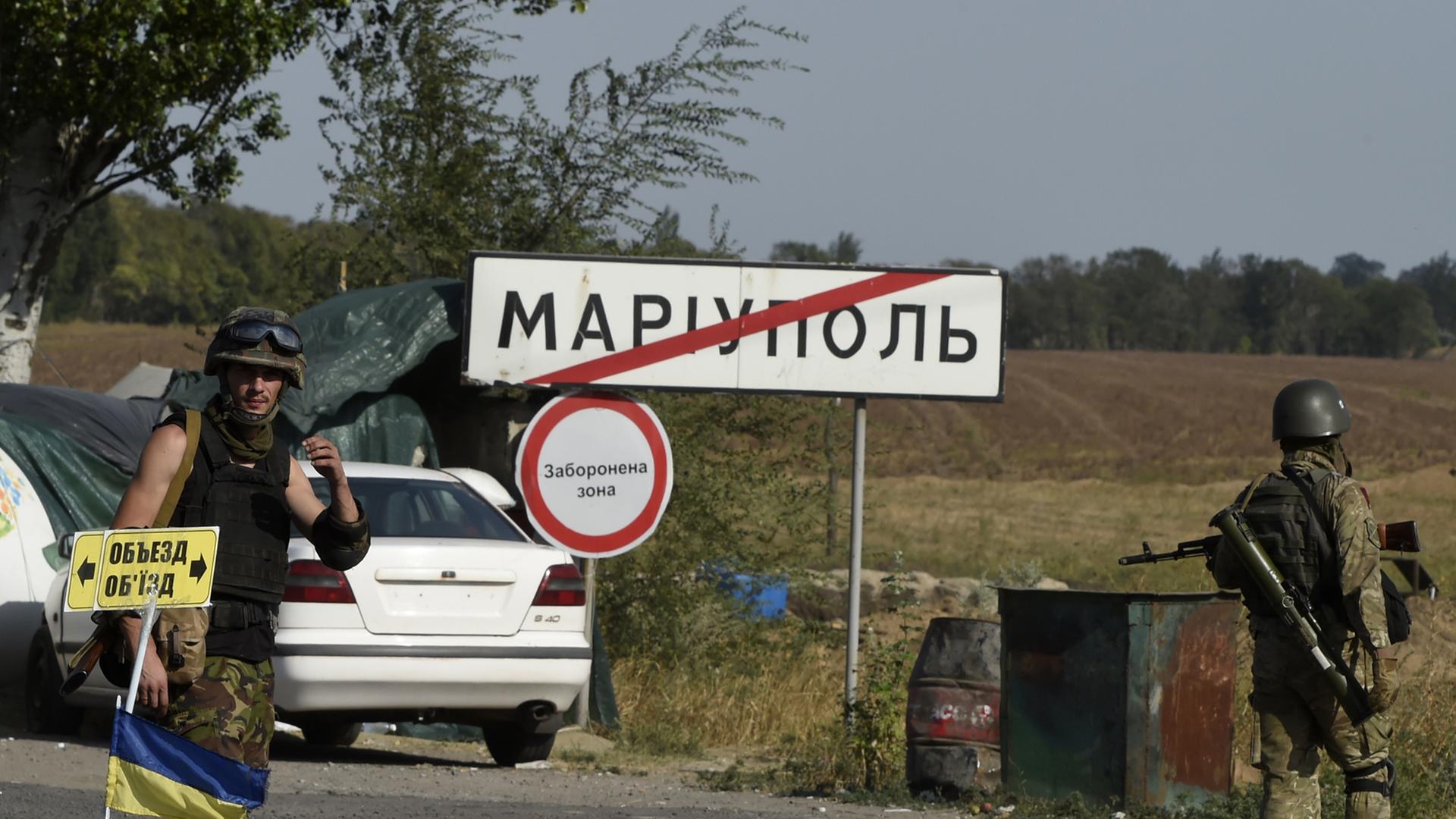 Ukrainische Soldaten vor einem Schild Mariupol.