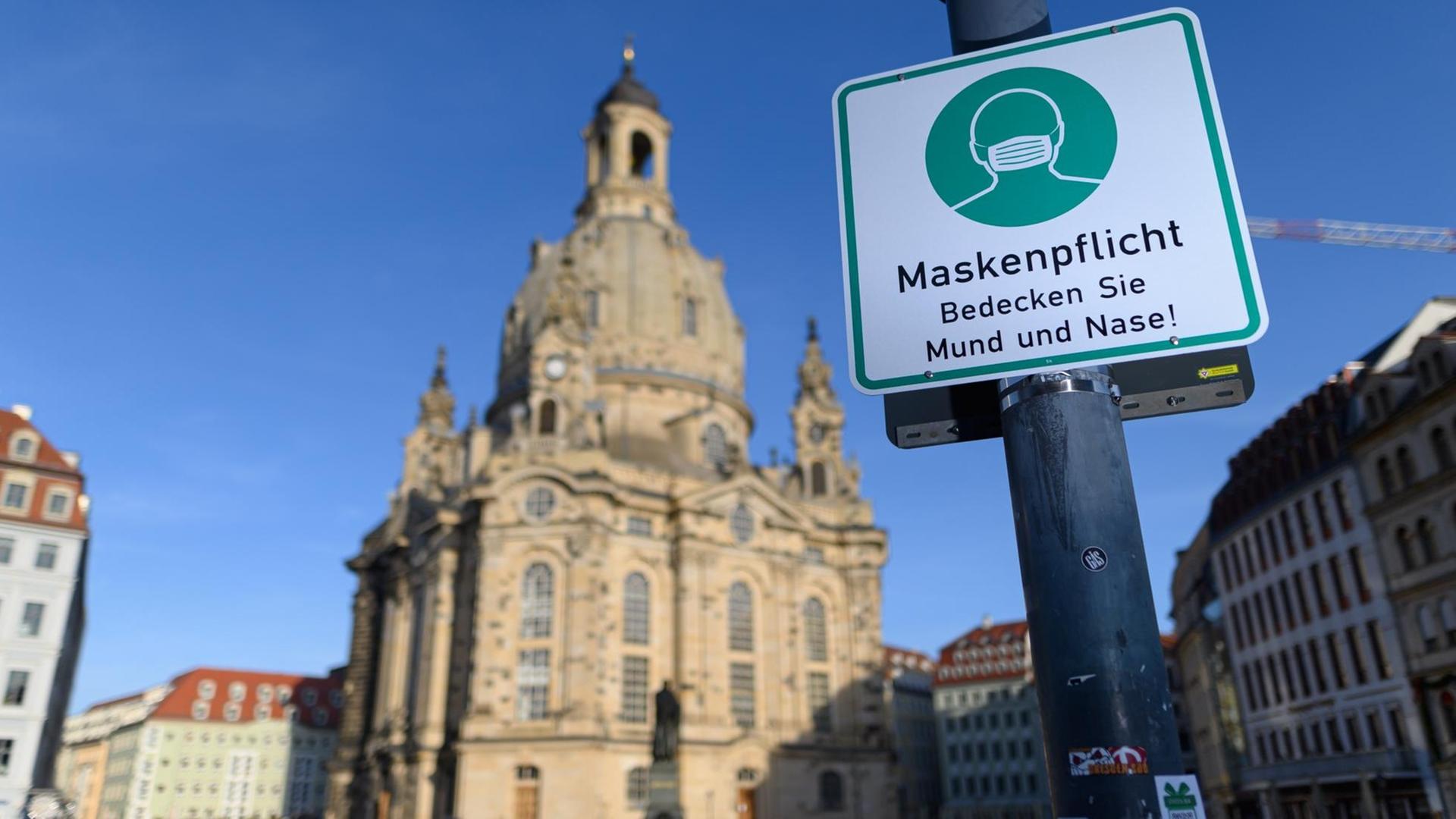 Vor der Frauen-Kirche in Dresden hängt an einer Laterne ein Hinweis-Schild zur Masken-Pflicht.