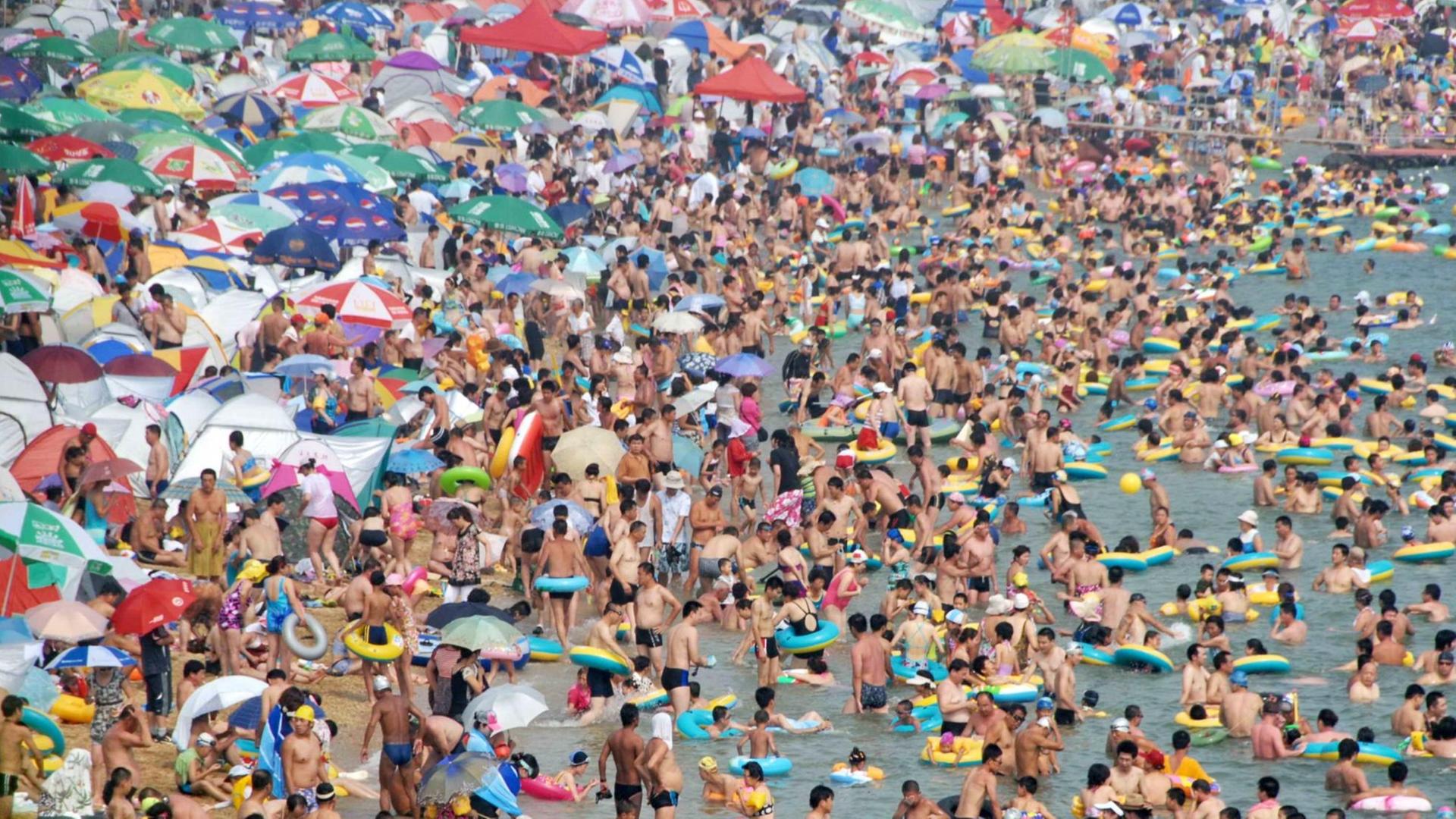 Badefreuden in der Bucht bei Qingdao in Chinas Shandong Provinz. Tausende Feriengäste am Strand von Qingdao am 01.August 2009