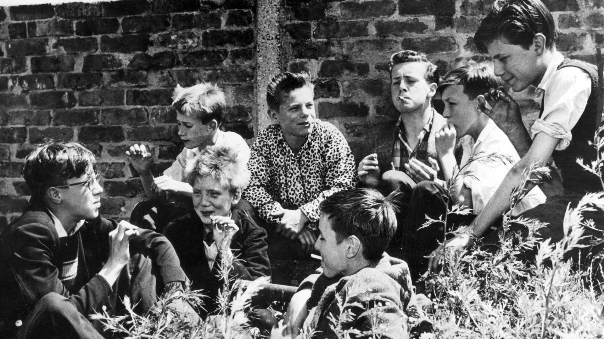 Eine Gruppe Jungen hat sich in London 1963 hinter einer Mauer versteckt