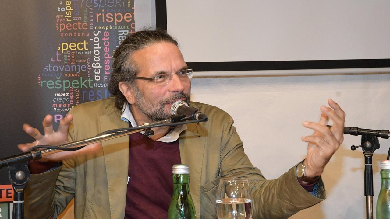 Dieses Bild zeigt den Philosophen und Professor für Kulturwissenschaft und Kulturtheorie Robert Pfaller, er gestikuliert am Diskussionstisch vor einem Mikrofon.