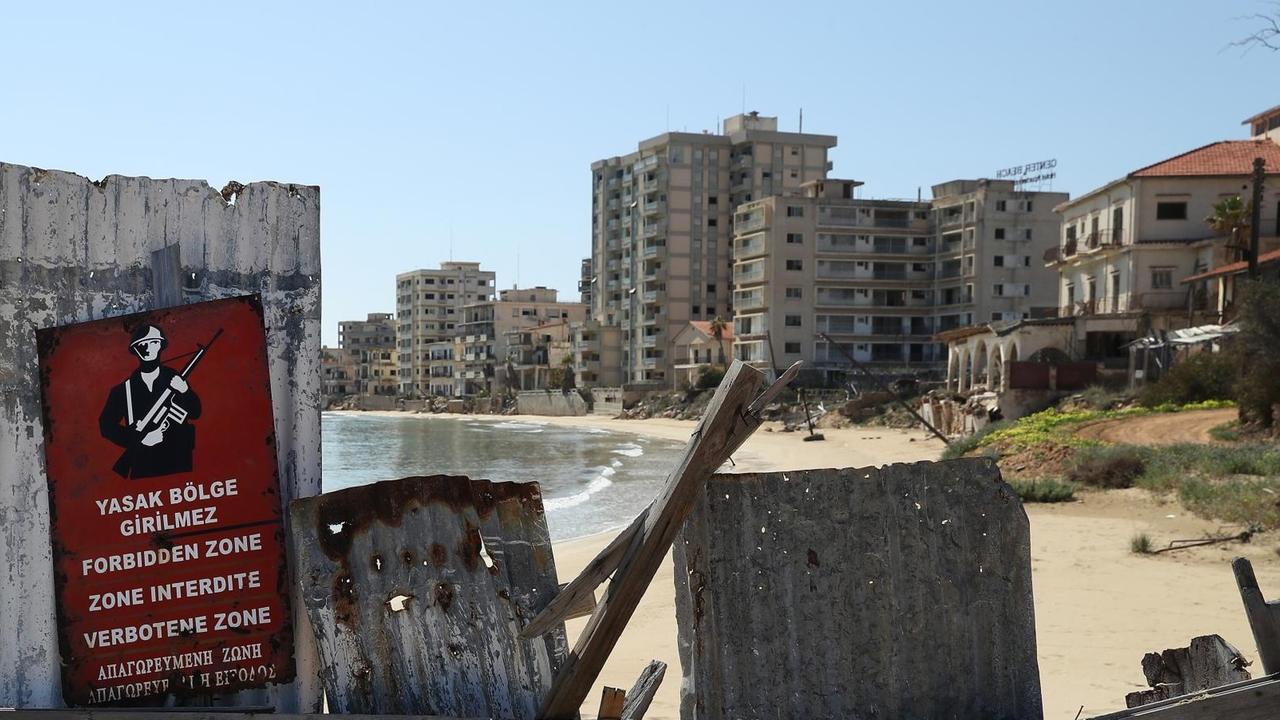 Ein Schild mit der Aufschrift "Verbotene Zone" vor einer Absperrung am Strand, dahinter sind die verfallenen Hotels des ehemaligen Touristenviertels Varosha in Famagusta zu sehen