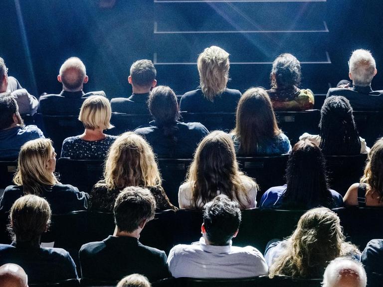 Publikum sitzt vor einer Bühne.