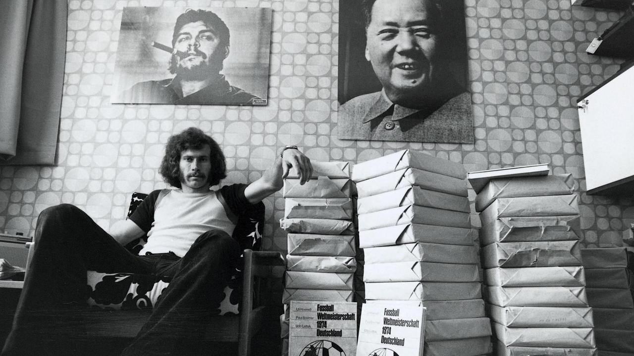 Der Fußballer Paul Breitner sitzt mit Bildbänden zur Fußballmeisterschaft auf einem Sessel, an der Wand hängen Poster von Mao und Che Guevara, 1974