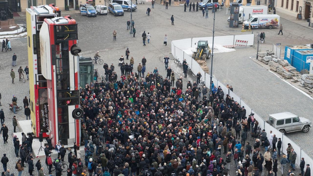 Demonstranten und Polizisten stehen am 07.02.2017 auf dem Neumarkt in Dresden (Sachsen) vor der Skulptur "Monument" des syrischen Künstlers Manaf Halbouni.