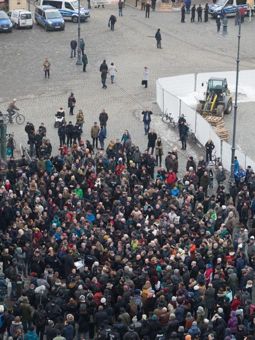 Demonstranten und Polizisten stehen am 07.02.2017 auf dem Neumarkt in Dresden (Sachsen) vor der Skulptur "Monument" des syrischen Künstlers Manaf Halbouni.