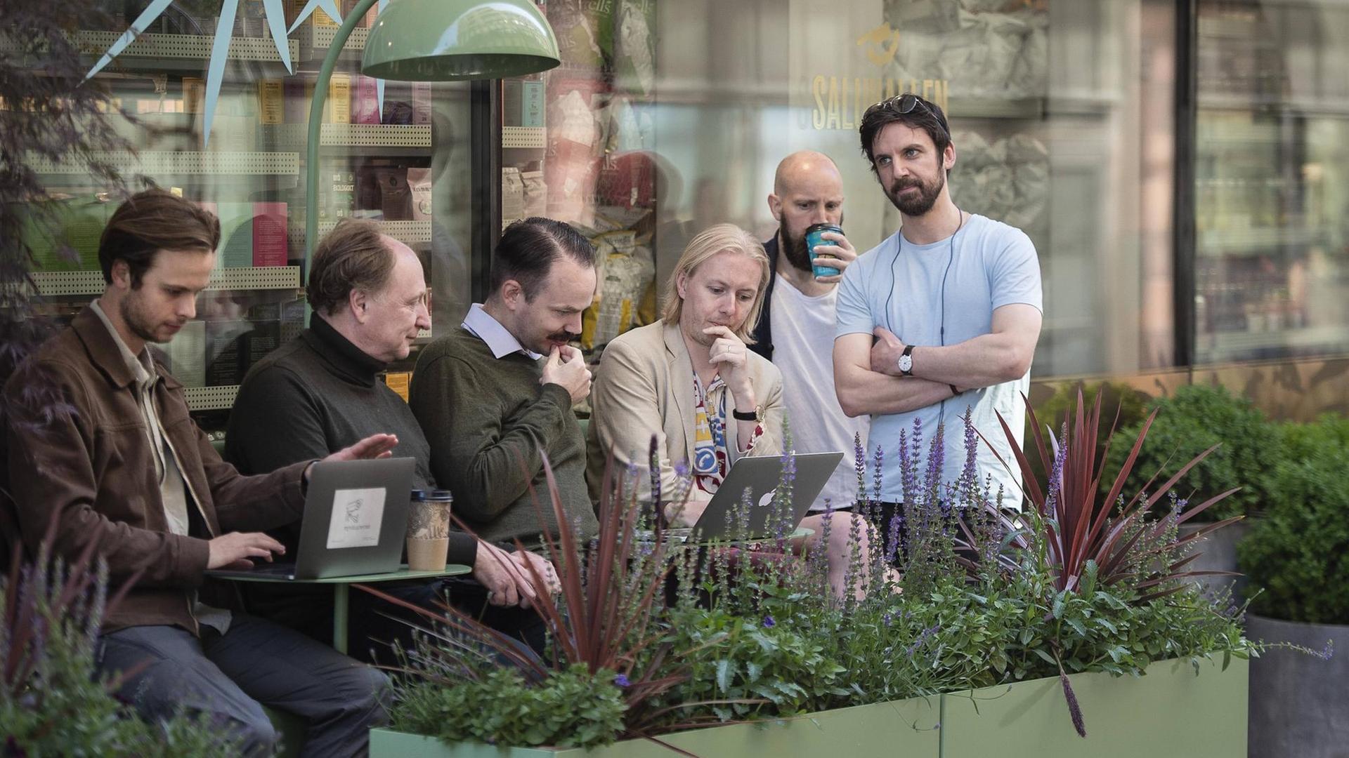 Menschen haben sich auf der Straße zu einer Gruppe zusammengefunden und schauen auf ein Laptop.
